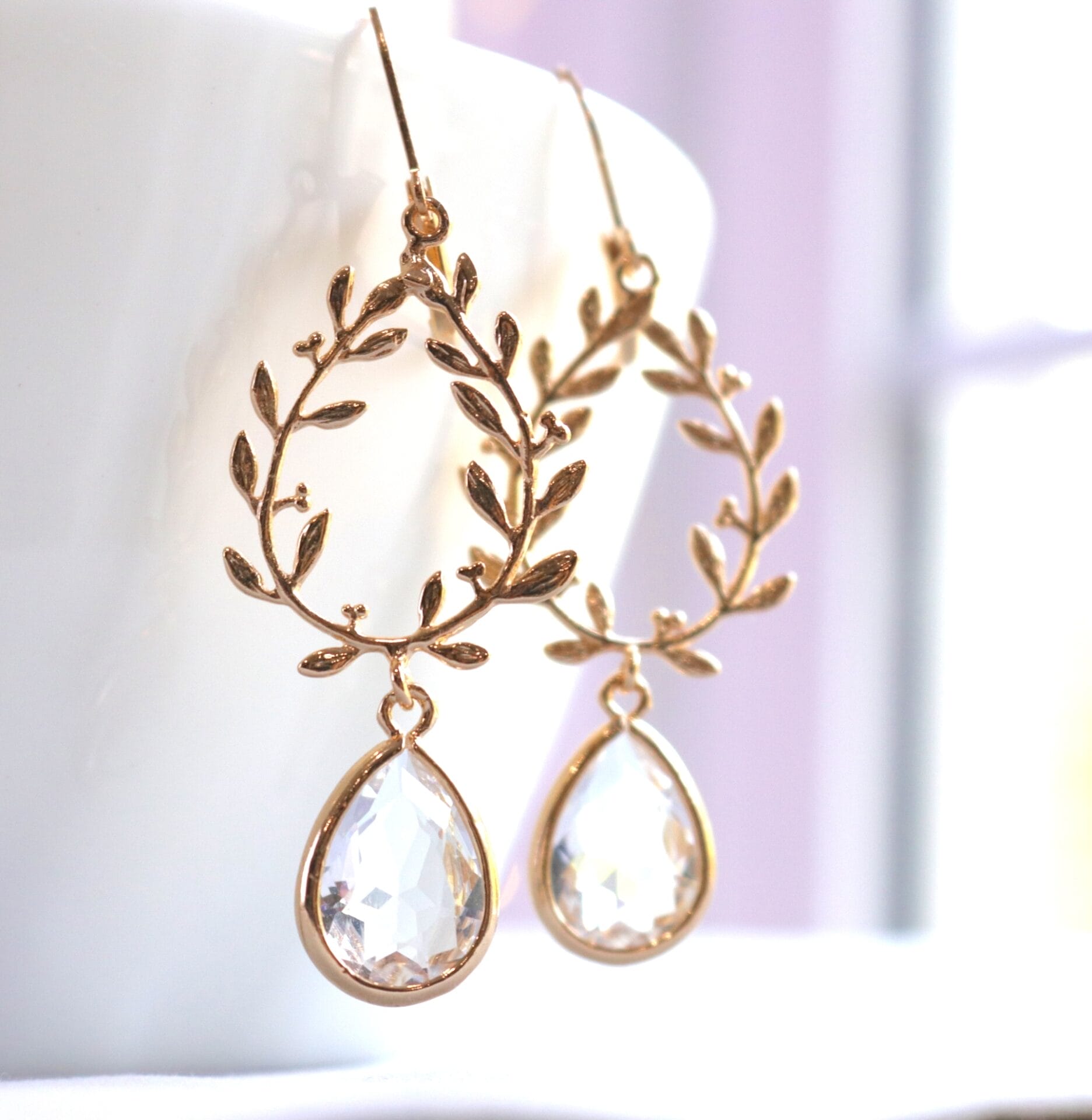 Gold olive laurel wreath leaf drop earrings with sparkling clear teardrop crystals. Perfect bridal, wedding, or evening jewelry for a timeless, elegant look.
